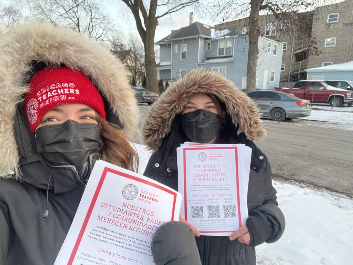 A CTU member and rep hold up flyers outside, wearing coats and masks
