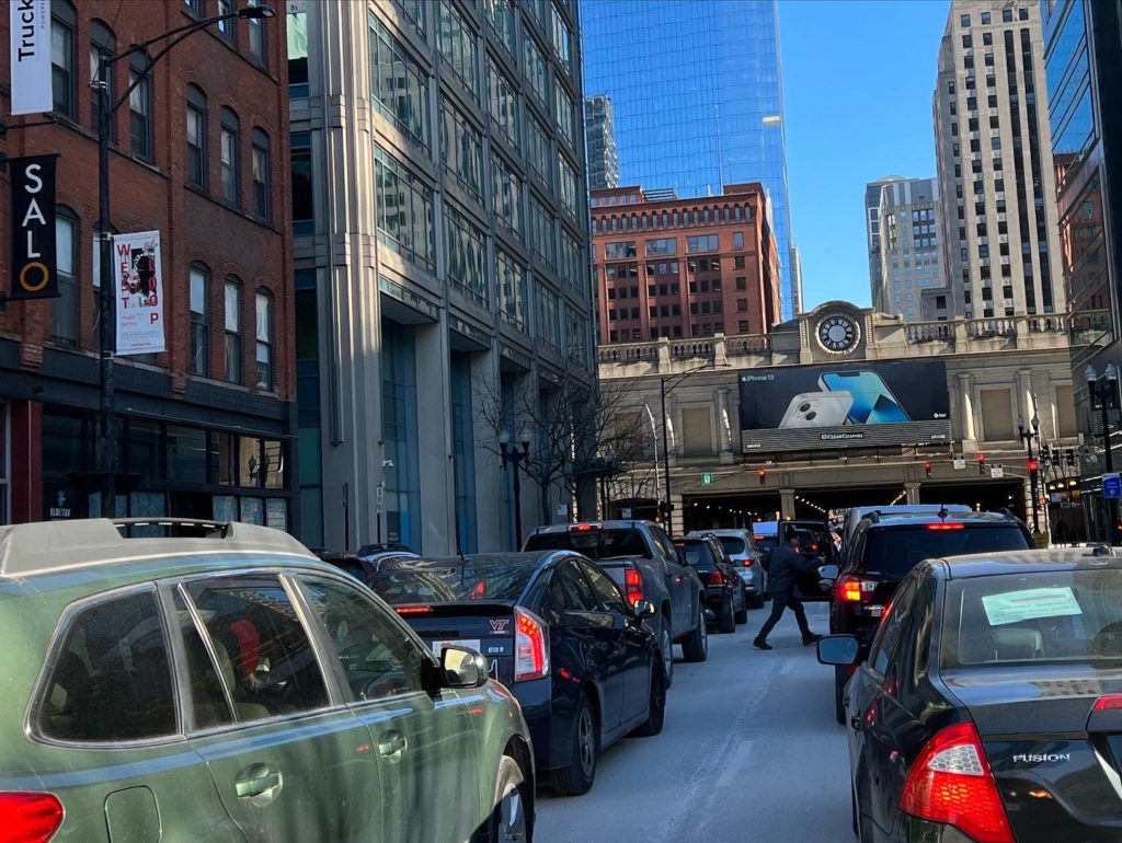 Cars crowd the two visible lanes of a narrow city street.